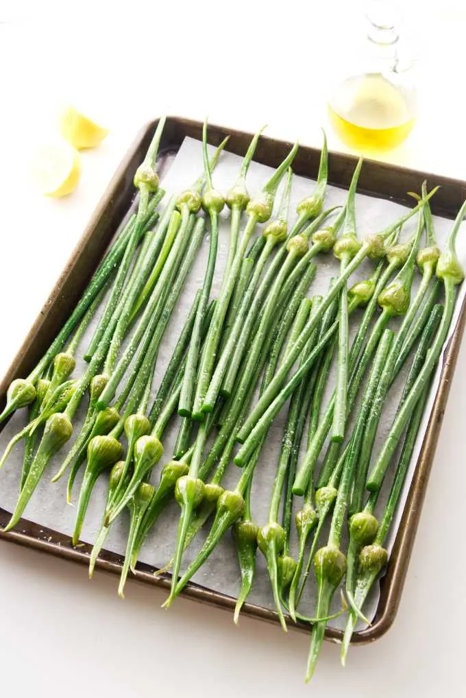 Fresh garlic spears on a baking sheet ready for the oven.