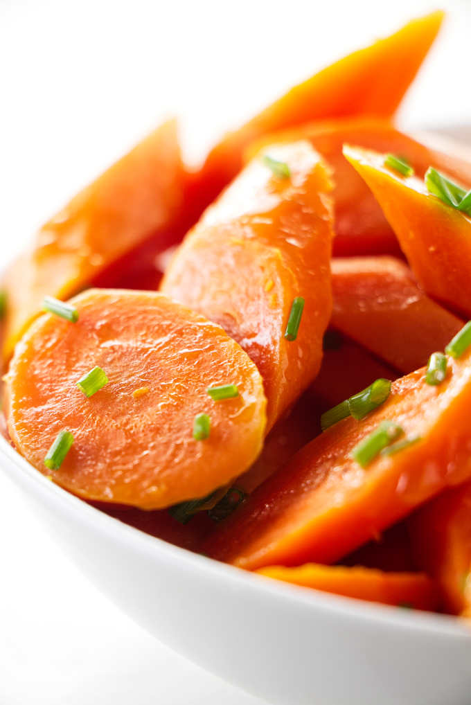 Steamed carrots in a bowl with chives sprinkled on top.