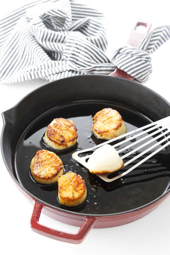 Scallops searing in a skillet.