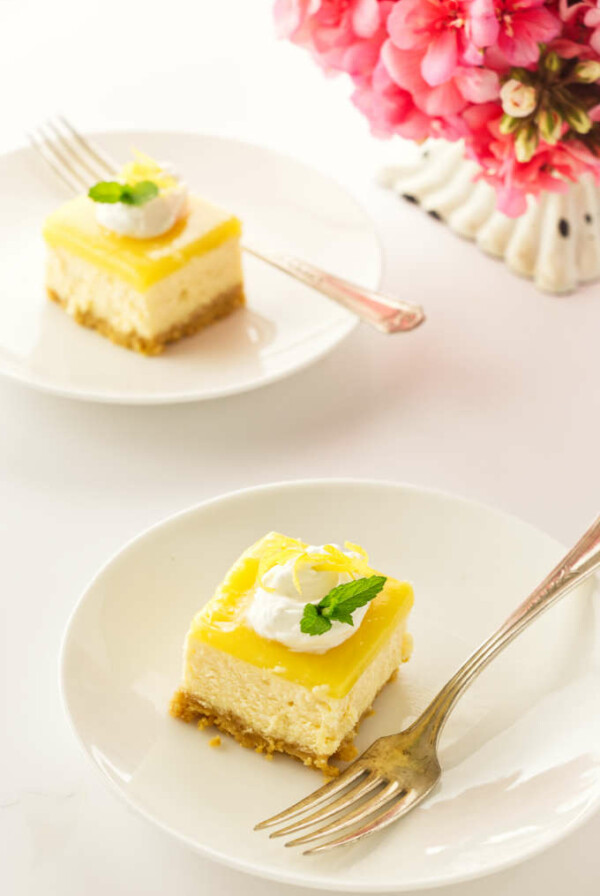 two servings of lemon cheesecake bars on plates with forks