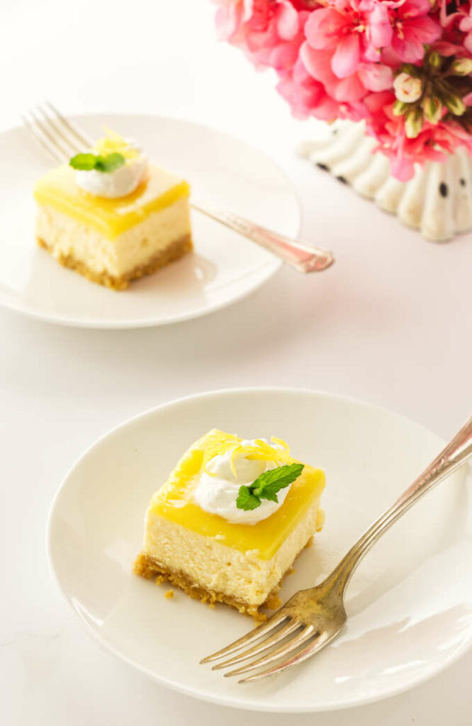 two servings of lemon cheesecake bars on plates with forks