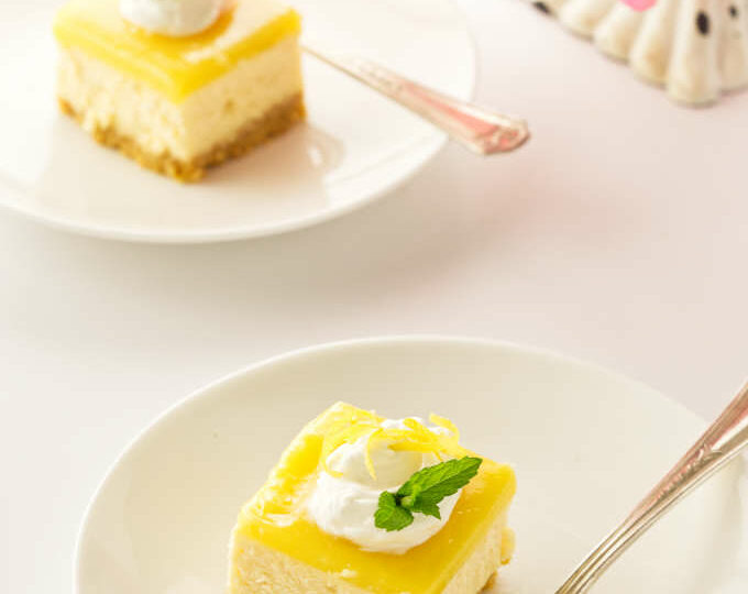 two servings of lemon cheesecake bars on plates with forks