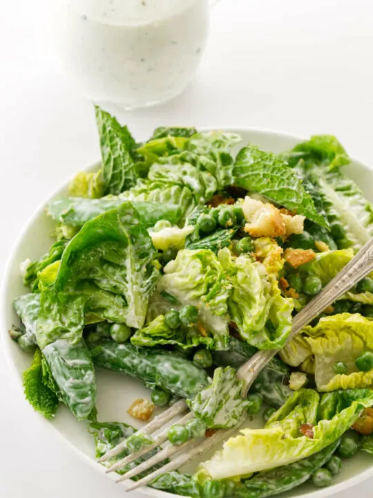 A serving of salad with fork, buttermilk ranch dressing in background