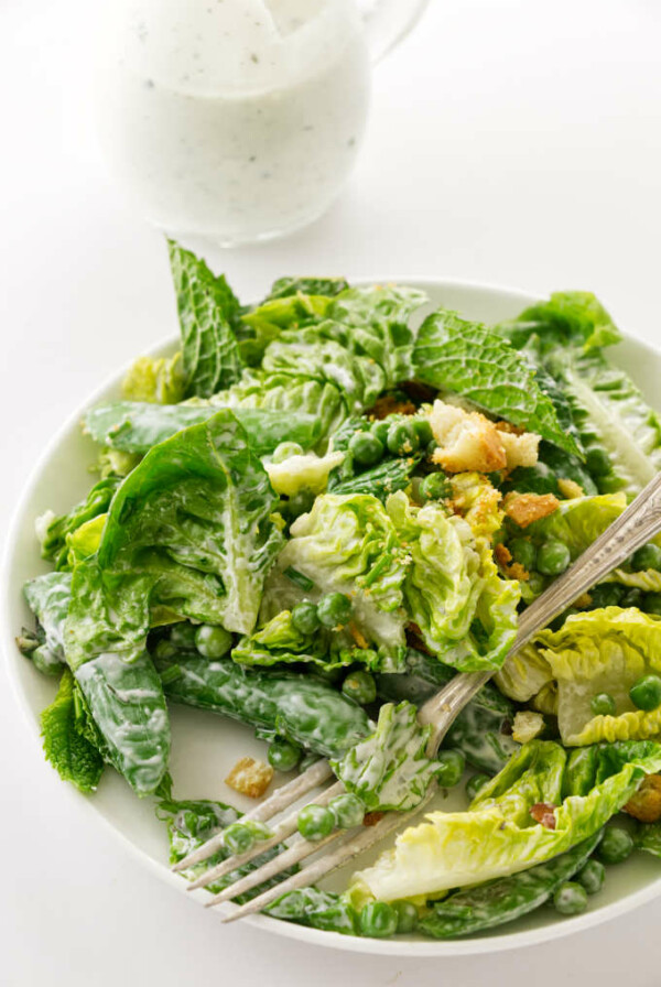 A serving of salad with fork, buttermilk ranch dressing in background