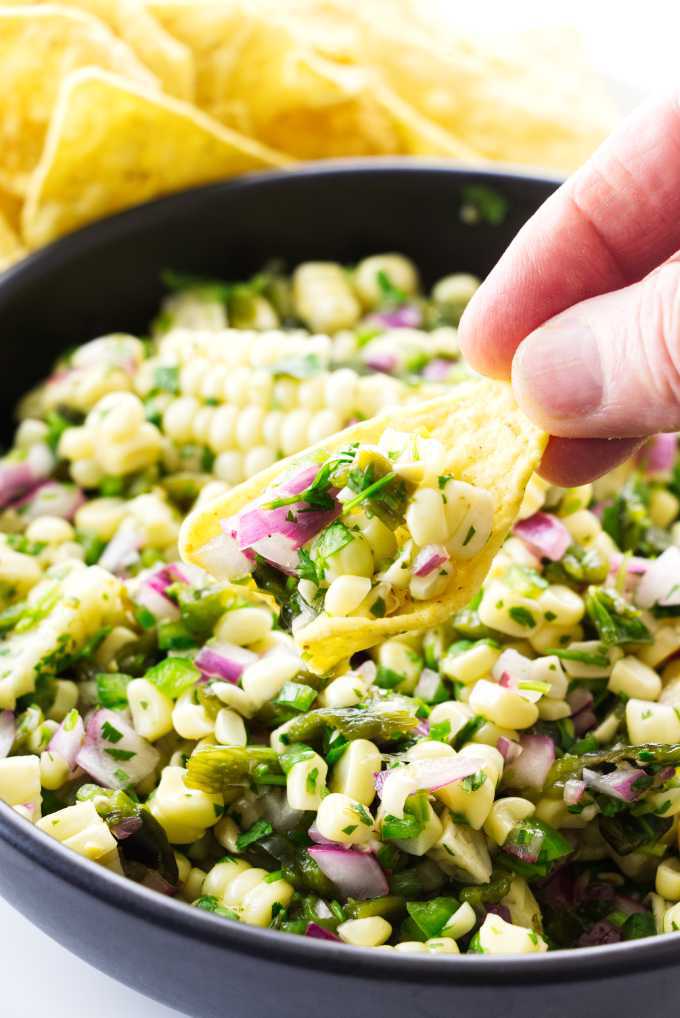 a bowl of chipotle corn salsa with a corn chip and salsa on it