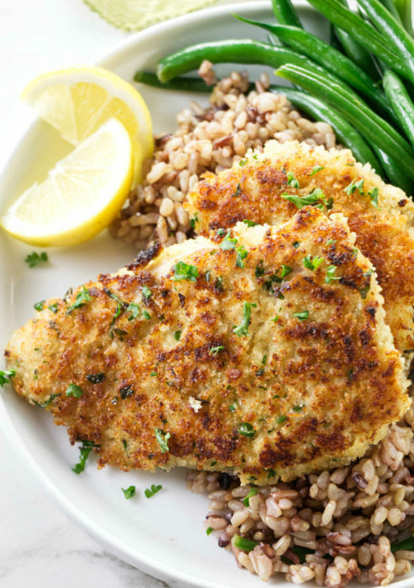 Two Panko crusted rockfish fillets on a dinner plate with rice and green beans.