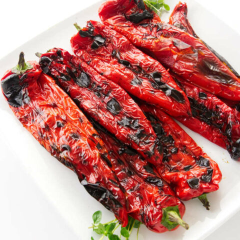 A serving plate filled with grilled Italian sweet peppers.