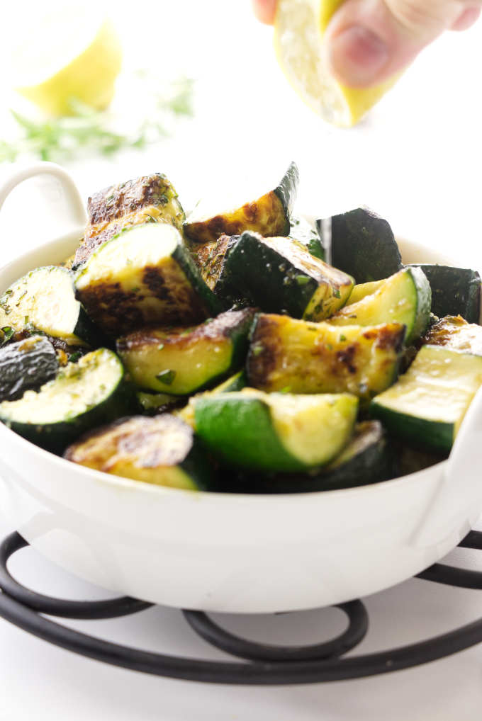Squeezing a lemon over sauteed zucchini.