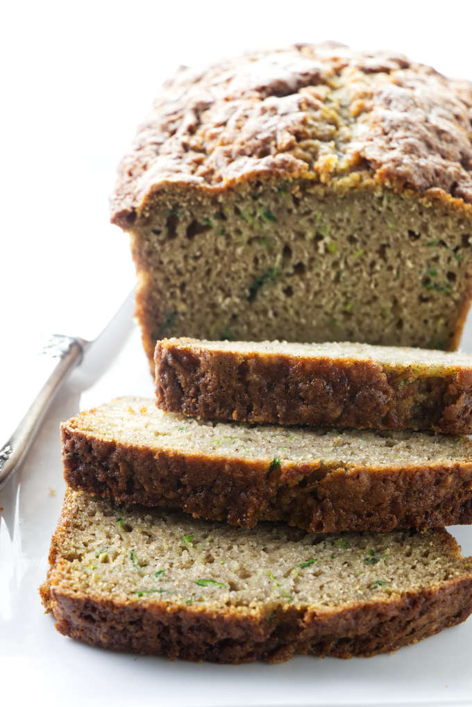 A sliced loaf of zucchini bread next to a knife.