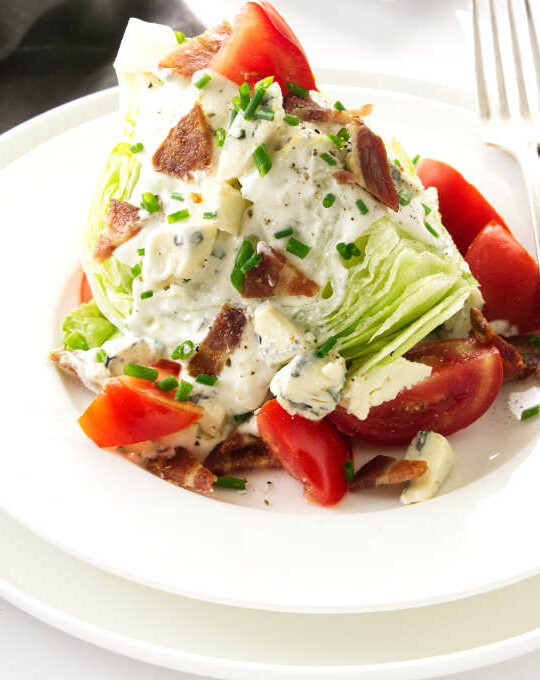 Serving of classic wedge salad on a plate with blue cheese dressing