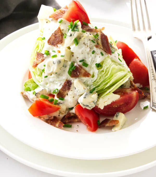 Serving of classic wedge salad on a plate with blue cheese dressing