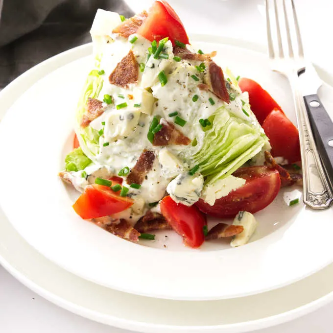 Serving of classic wedge salad on a plate with blue cheese dressing