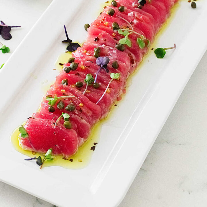 A serving plate with tuna crudo and garnish.