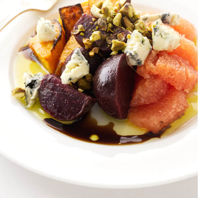 Close up view of a roasted squash and beet salad with grapefruit, blue cheese and pistachios