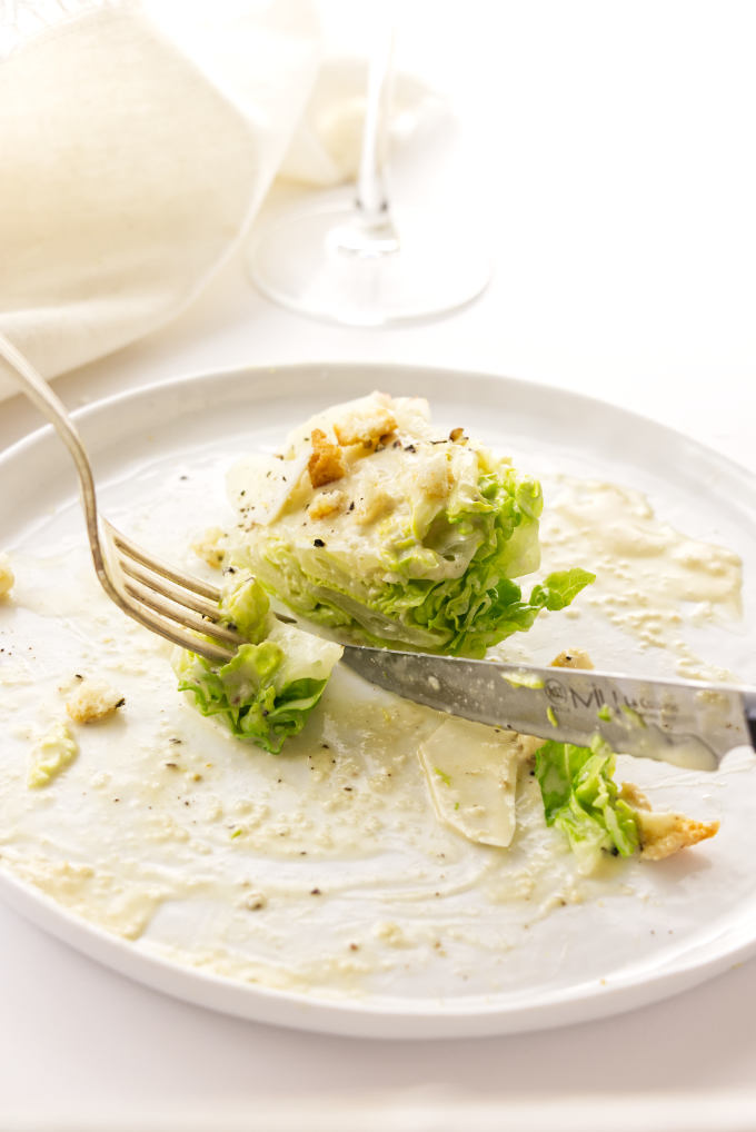 knife and fork cutting into a bite of Little Gem lettuce with caesar dressing