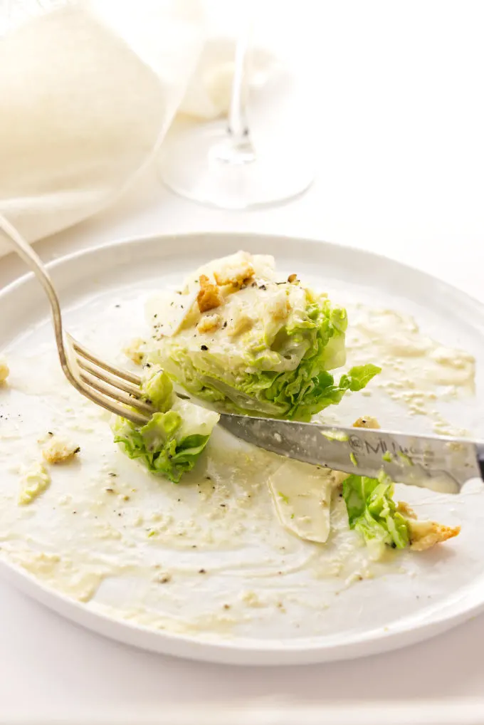knife and fork cutting into a bite of Little Gem lettuce with caesar dressing