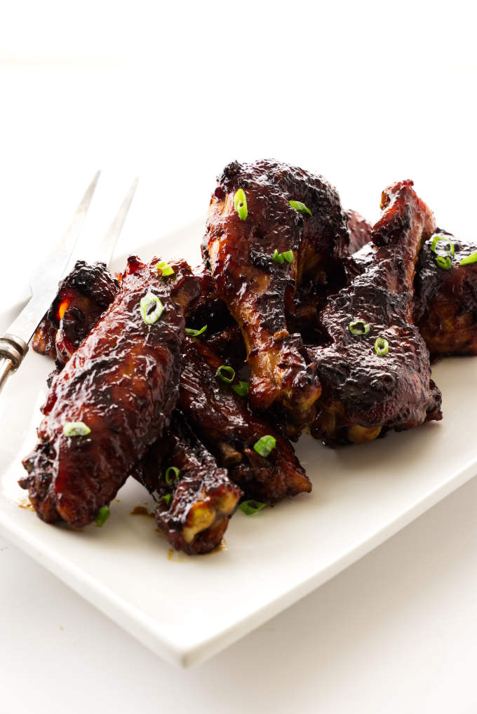 Platter with sticky teriyaki turkey wings, serving fork on edge of plate