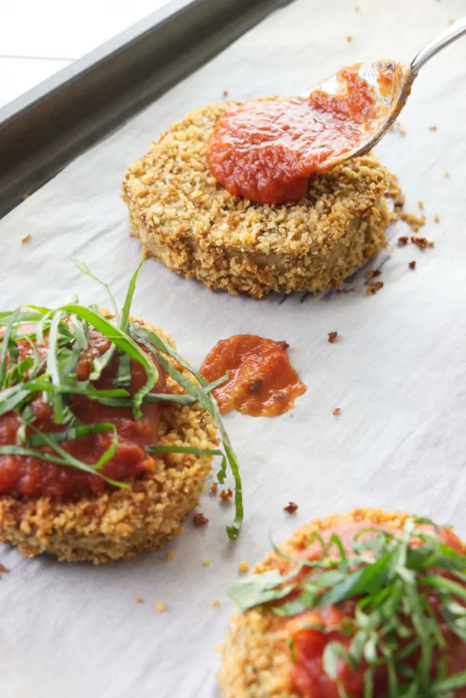 Adding marinara sauce to eggplant slices.