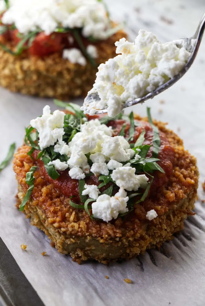 Topping eggplant steaks with goat cheese.