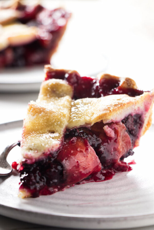 A slice of blackberry peach pie on a plate.