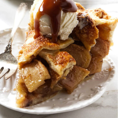 A slice of caramel apple pie with vanilla ice cream and caramel sauce on top.