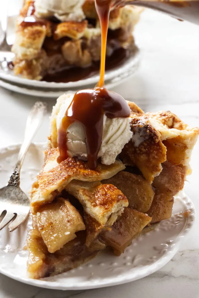 Pouring caramel sauce over an apple pie with vanilla ice cream.
