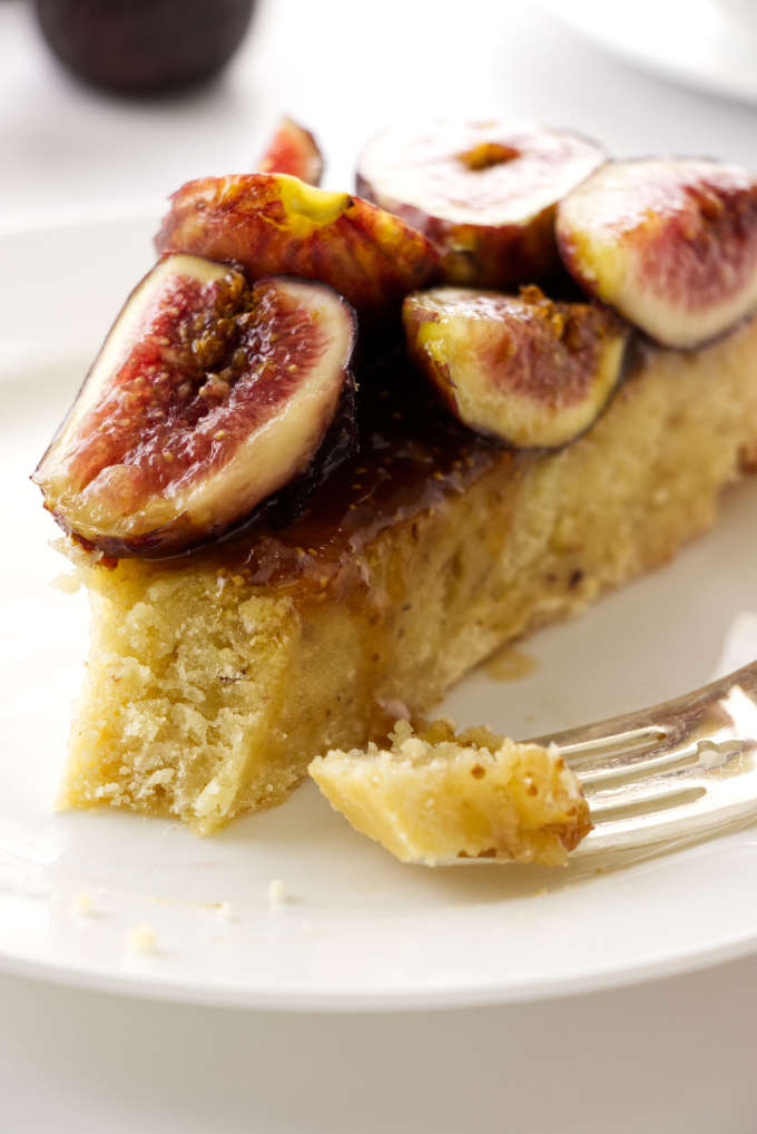 Frangipane fig tart on a serving plate with a bite on a fork