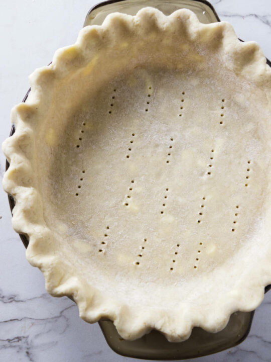 An unbaked gluten free pie crust in a glass pie dish.