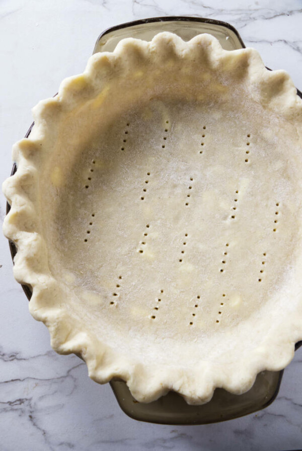 An unbaked gluten free pie crust in a glass pie dish.