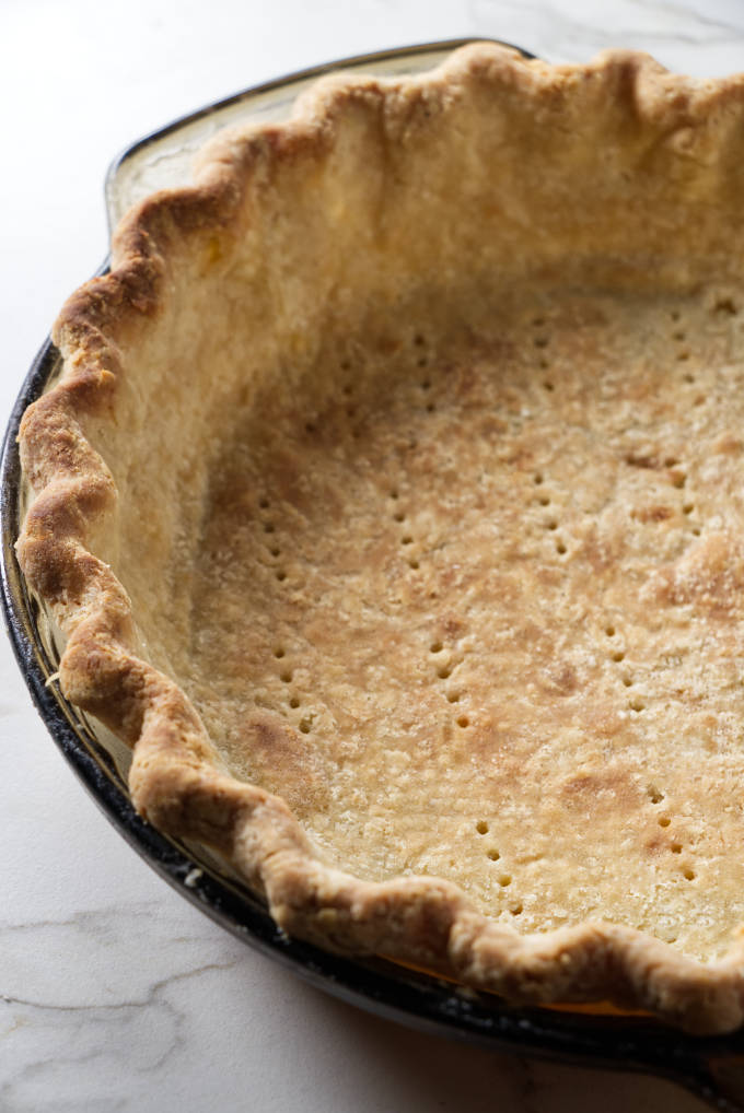 A baked pie crust in a glass pie dish.