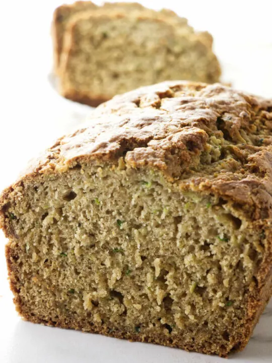 A loaf of gluten free zucchini bread sliced open to see the tender texture.