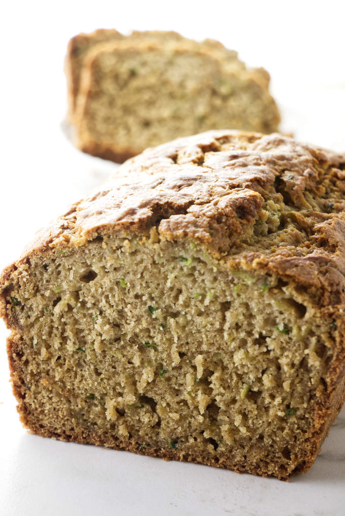 A loaf of gluten free zucchini bread sliced open to see the tender texture.