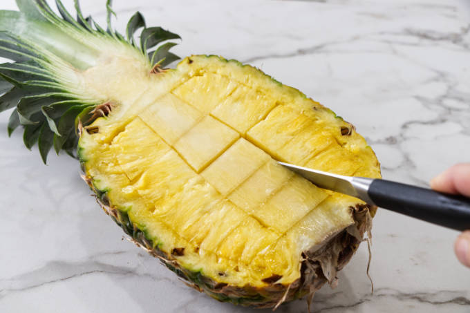 Slicing down the core of a pineapple half.