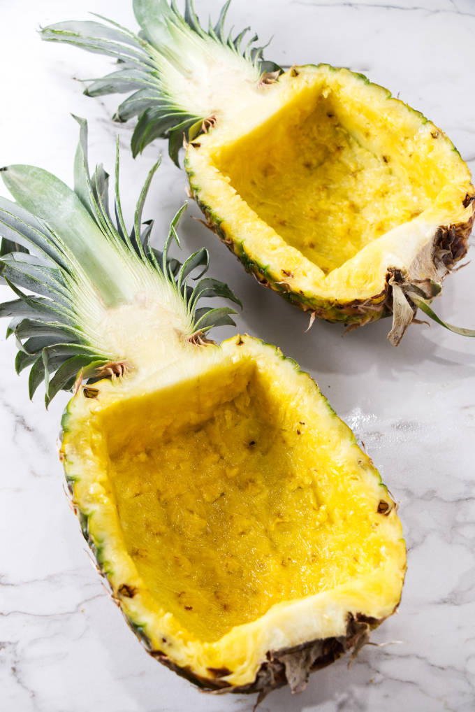 Two halves of a pineapple carved into bowls.