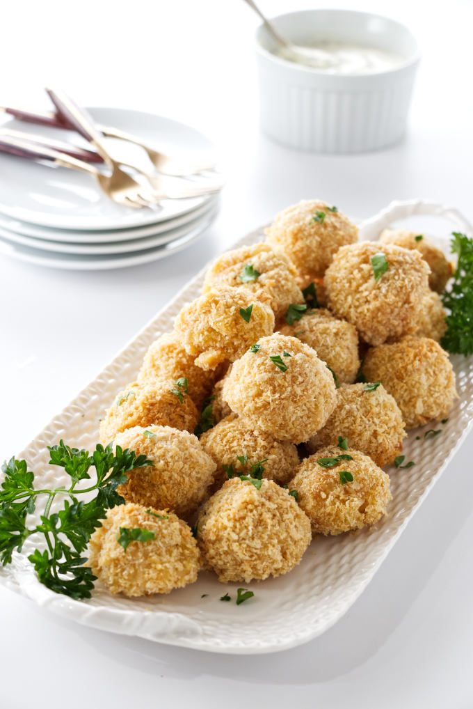 plate of mac 'n cheese bites, serving plates and ranch dip in the background