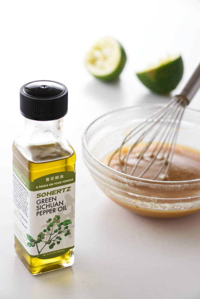 A dish of Miso glaze with a whisk, sichuan oil in foreground and limes in background