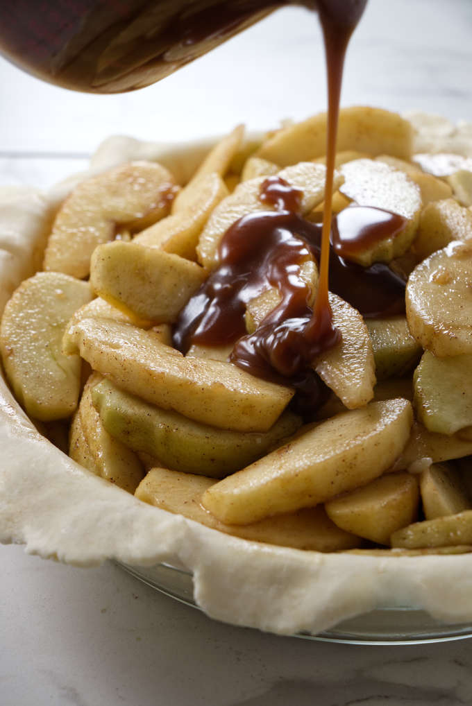 Drizzling caramel sauce over apple pie filling.