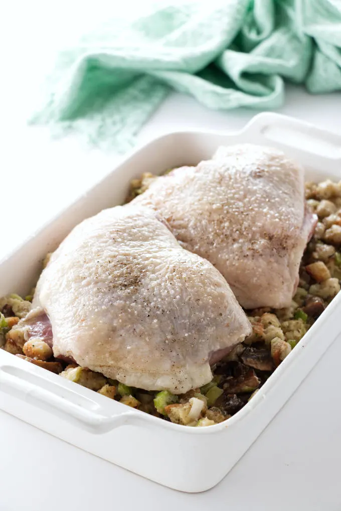 Two turkey thighs on a bed of stuffing, ready to be roasted