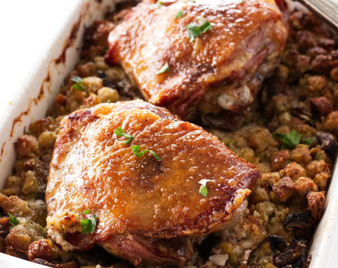 Casserole dish with stuffing topped with two turkey thigs