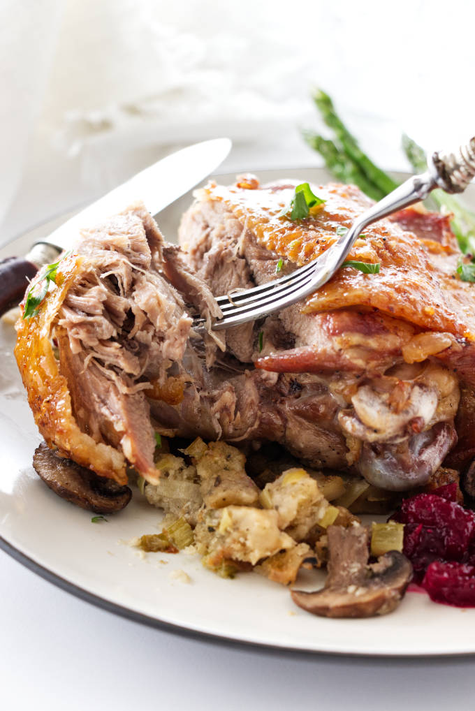 close up view of a roasted turkey thigh on a mound of stuffing