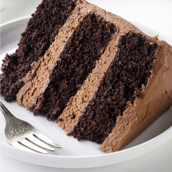 A slice of chocolate cake with chocolate buttercream frosting.