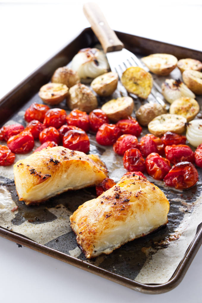 Sheet pan with baked sea bass, tomatoes, potatoes and onions