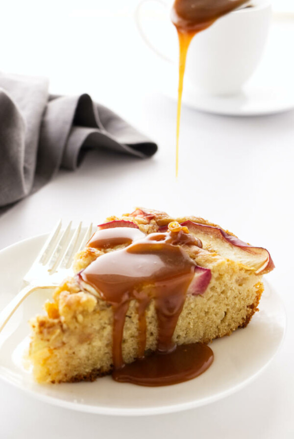 Caramel sauce being poured on a slice of apple skillet cake