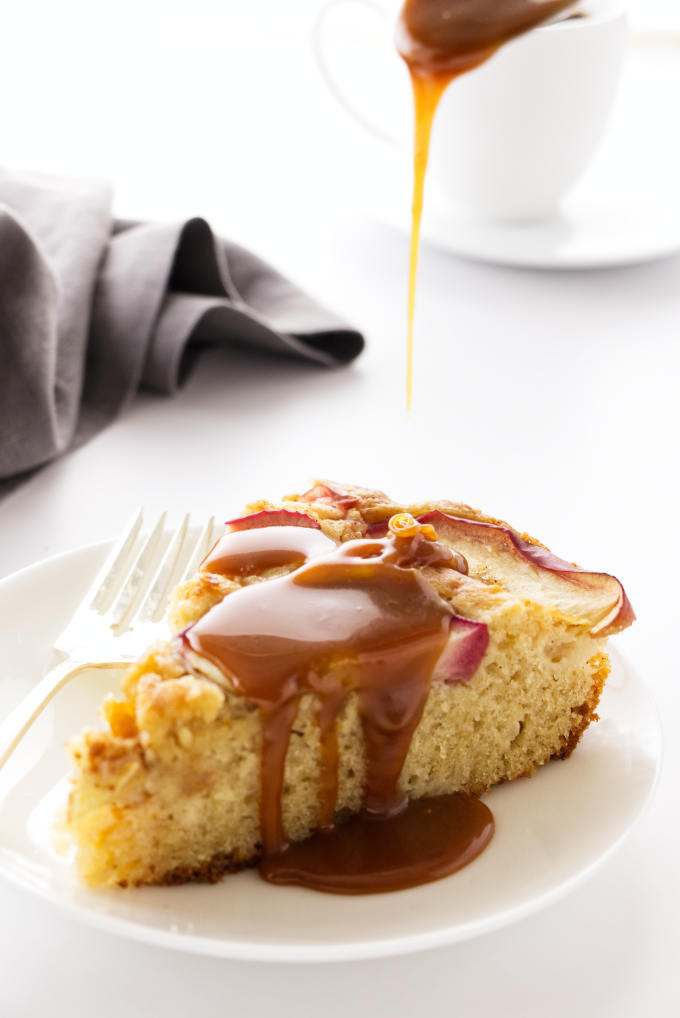 Caramel sauce being poured on a slice of apple skillet cake