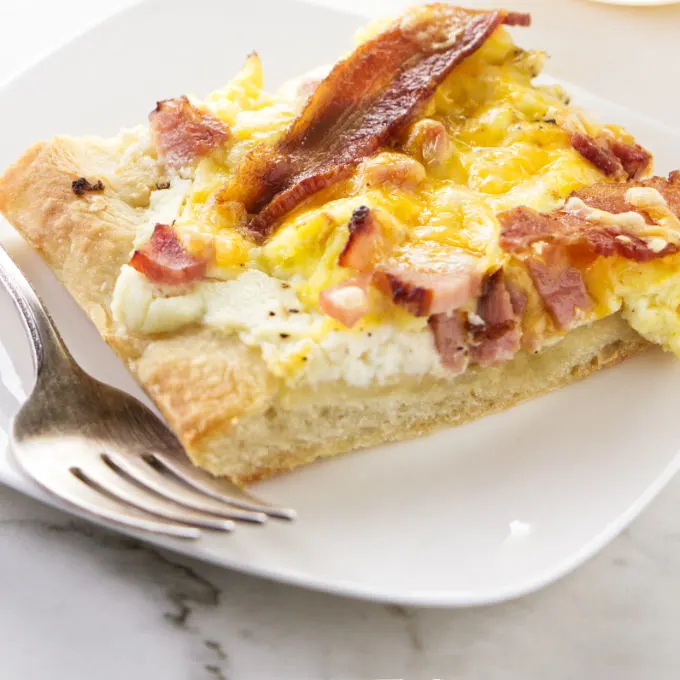 A slice of breakfast pizza on a serving plate.