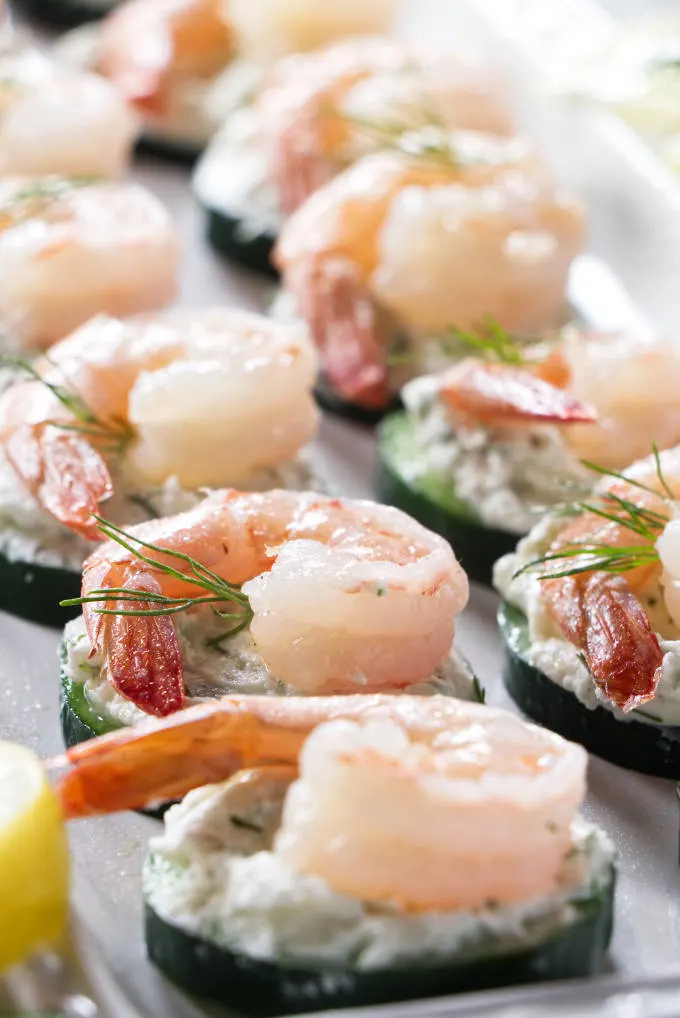 Bite size appetizers made with cucumber, cream cheese, and shrimp on a serving platter.