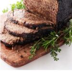 A sauerbraten roast sliced on a cutting board.