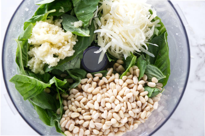 Combining basil, cheese, garlic, pine nuts and salt in a food processor.