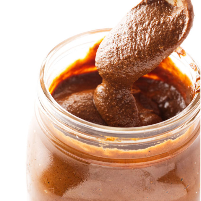 Pouring mole sauce into a jar.