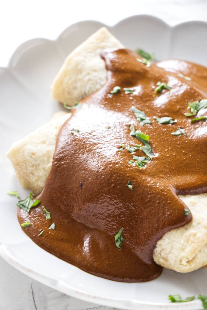 Two mole burritos on a white plate.